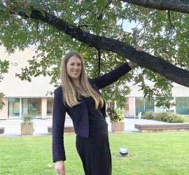 Elina yliopiston keskusaukiolla, päärakennus taustalla, käsi puun oksasta kiinni